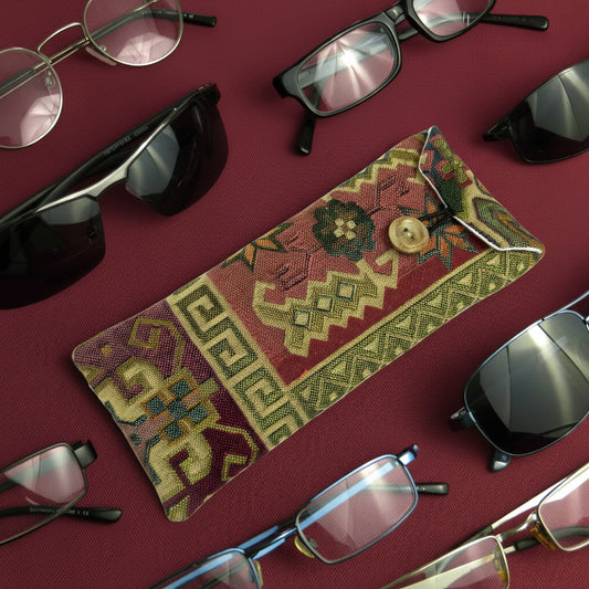Soft padded eyeglass pouch on a burgundy background with multiple styles of eyeglasses