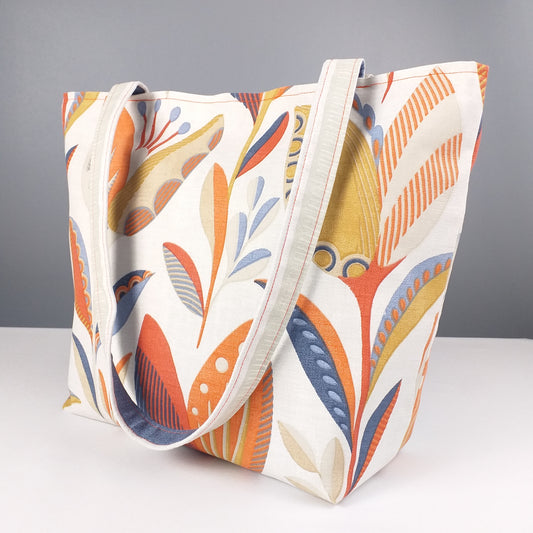 Large tote bag with shades of burnt orange, ochre, and denim blue tulip design on off-white background