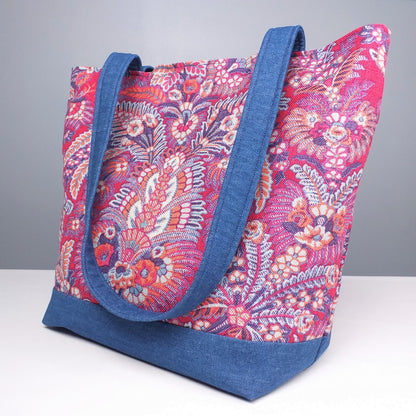 Side view of a large tote bag with multi-colour floral pattern, solid blue denim colour base