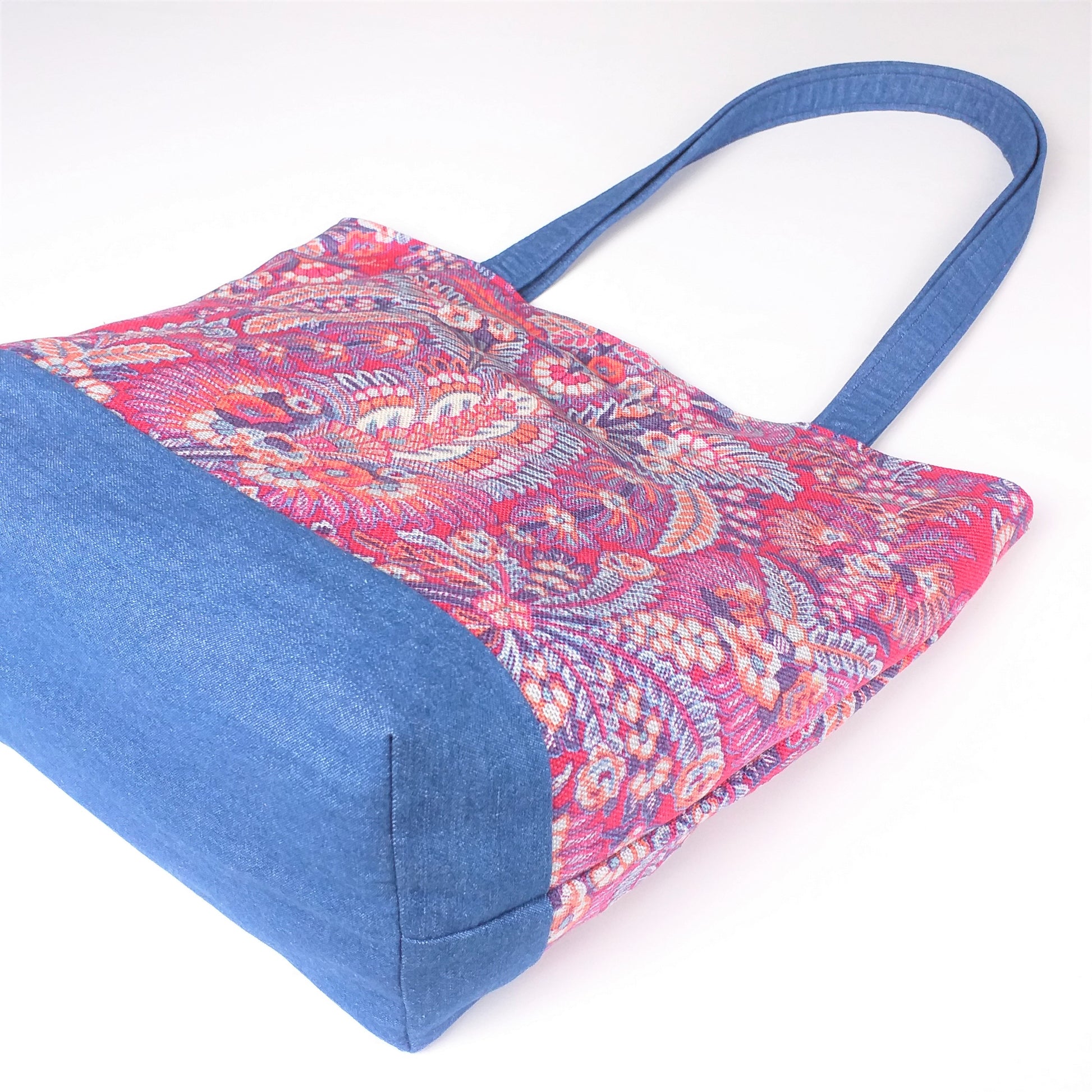 Bottom view of a large tote bag with multi-colour floral pattern, solid blue denim colour base