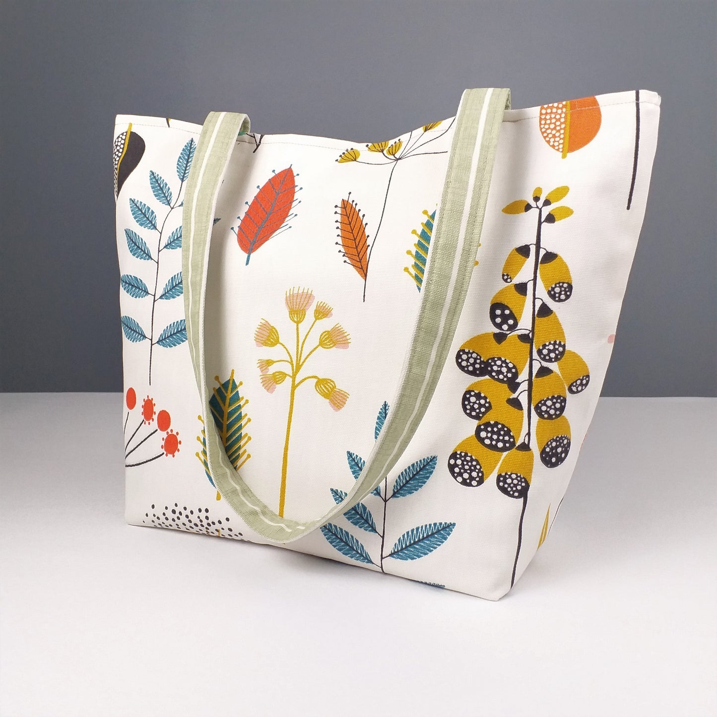 Side view of a large tote bag with multi-colour wild flowers design on an off-white background