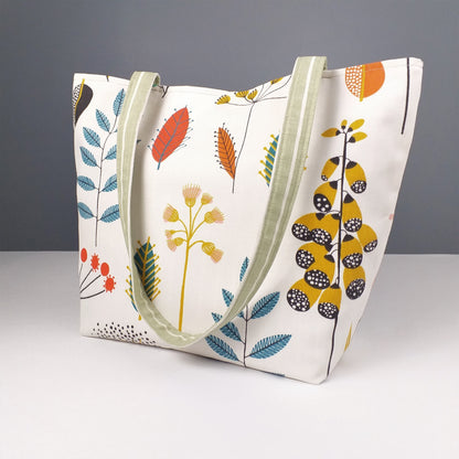 Side view of a large tote bag with multi-colour wild flowers design on an off-white background