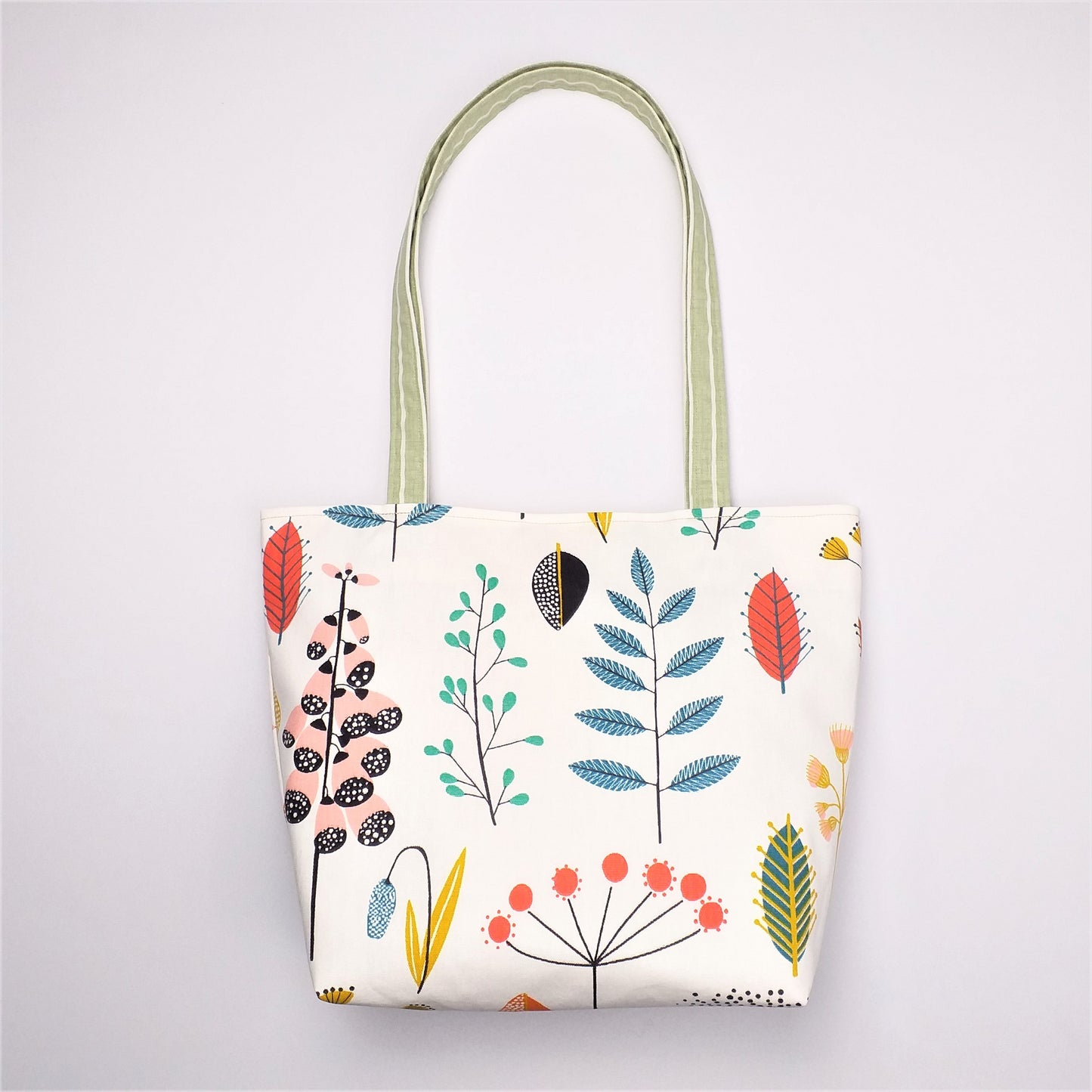 Front view of a large tote bag with multi-colour wild flowers design on off-white background