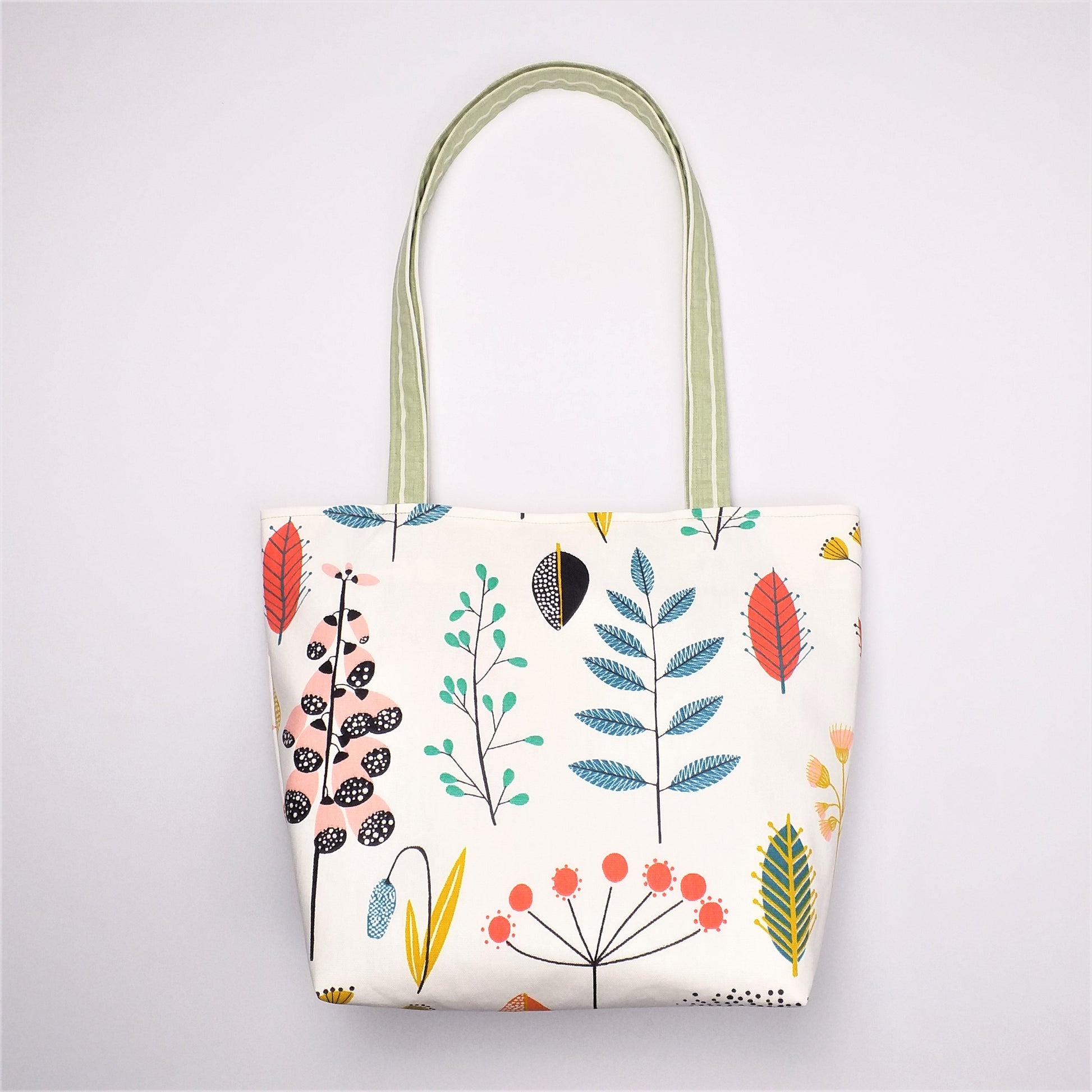 Front view of a large tote bag with multi-colour wild flowers design on off-white background
