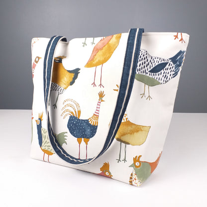 Side view of a large tote bag with multi-colour hens design on beige background