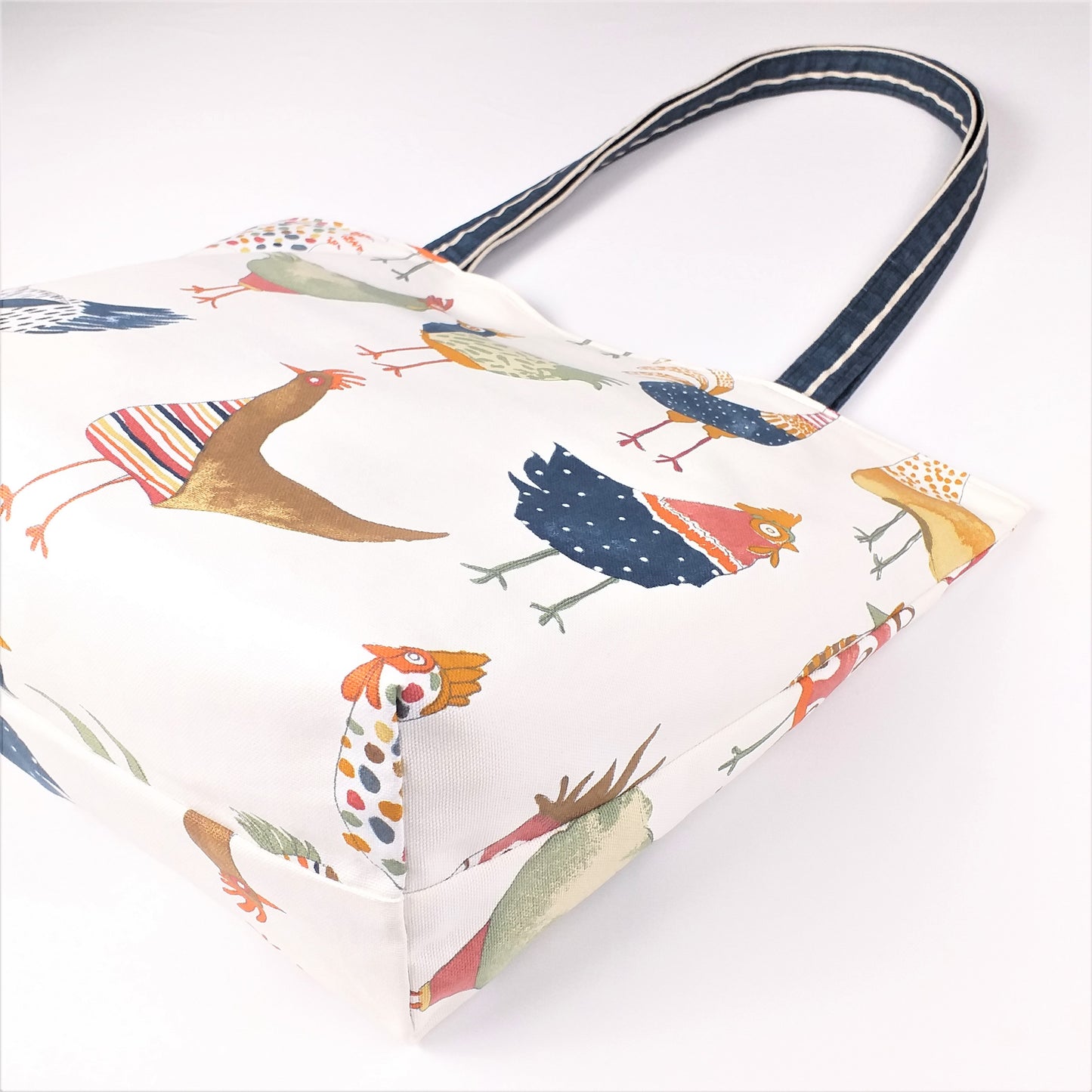 Bottom view of a large tote bag with multi-colour hens design on beige background