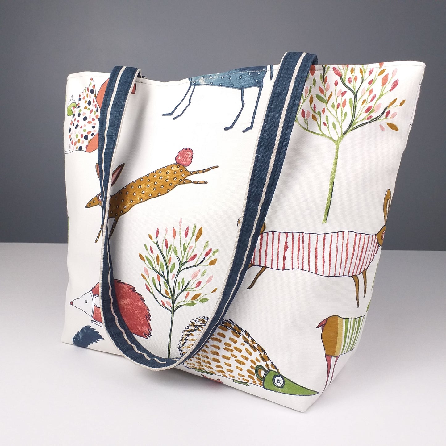 Large tote bag with multi-colour deer, foxes, squirrels, rabbits, and hedgehogs design on off-white background