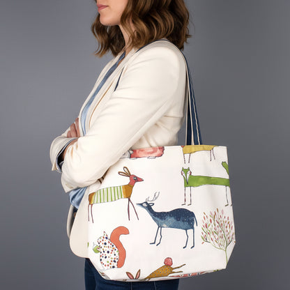Handmade large cotton tote bag with multi-colour deer, foxes, squirrels, rabbits, and hedgehogs design on off-white background with shoulder straps