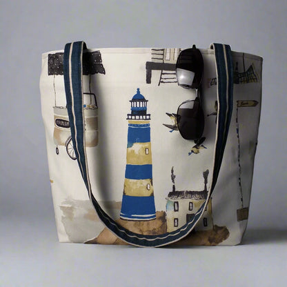 Large tote bag with multi-colour beach huts, lighthouse, seaside shops design on off-white background