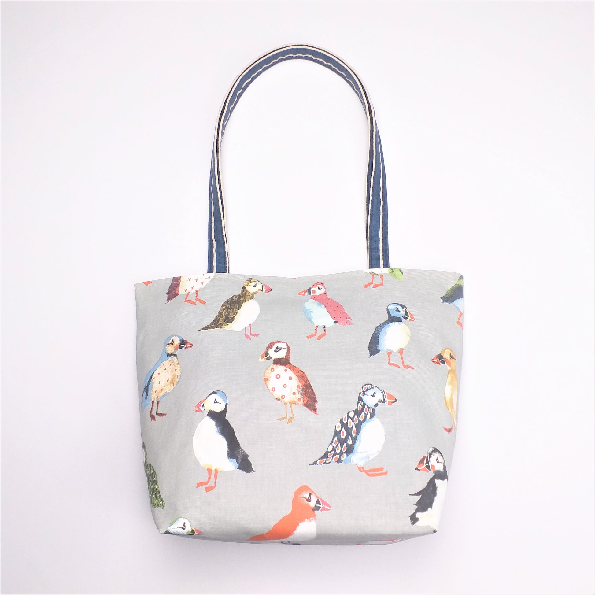 Front view of a large tote bag with multi-colour puffins design on grey background