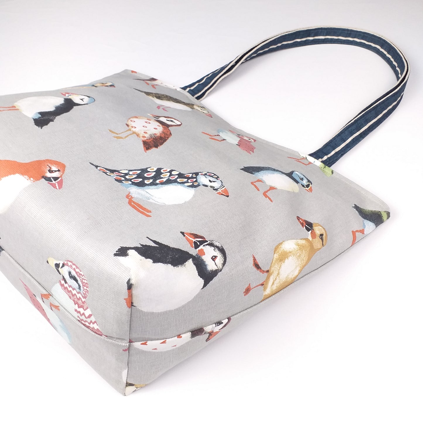 Bottom view of a large tote bag with multi-colour puffins design on grey background