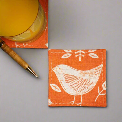 Square coasters with white bird design on orange background