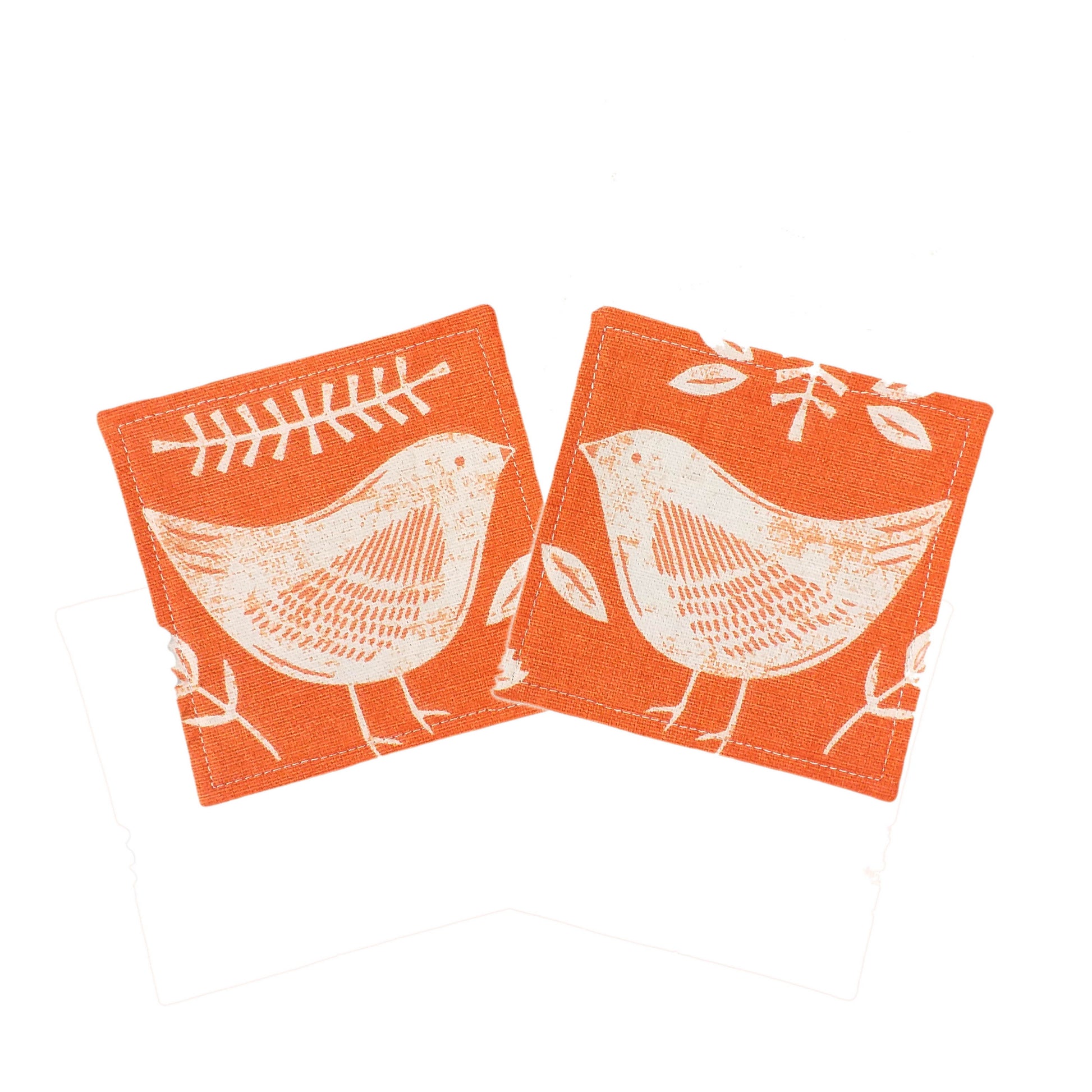 Square coasters with white bird design on orange background