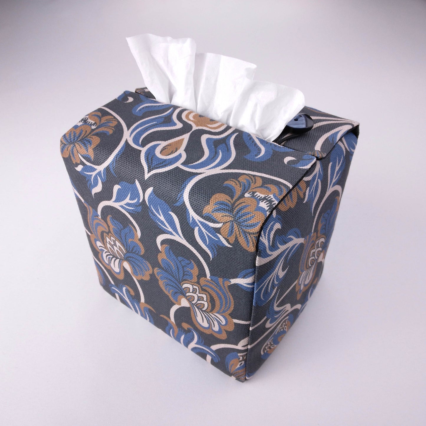 Back view of square tissue box cover with white, brown, and blue baroque style floral design on navy background
