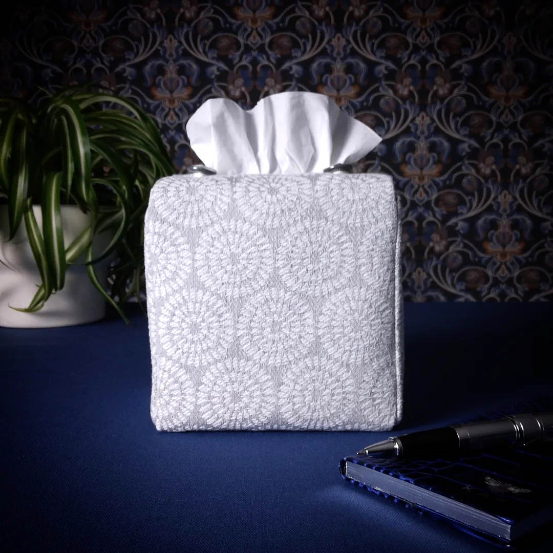 Square tissue box cover with a pen, notebook, and plant