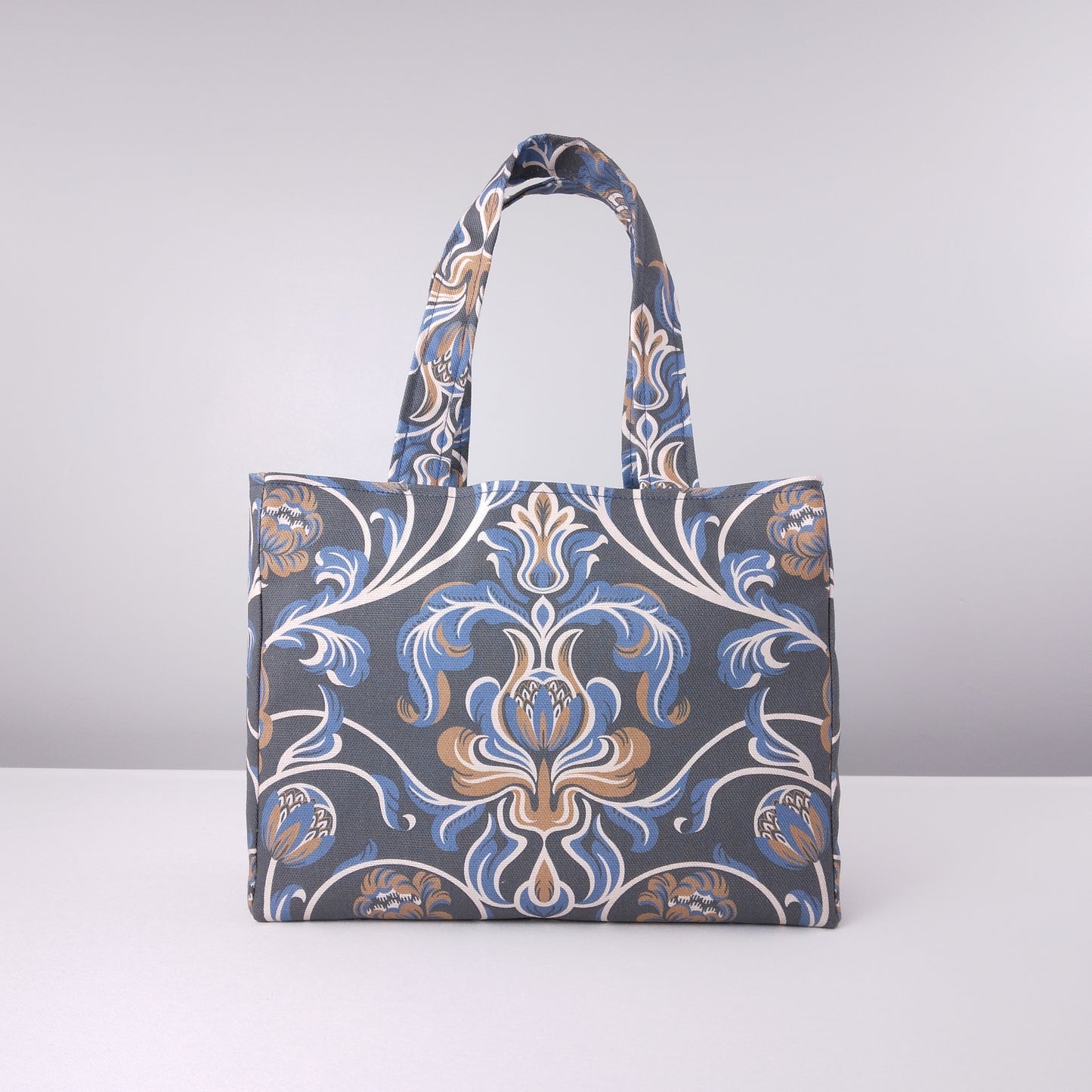Front view of a mini tote bag with white, brown, and blue baroque style floral design on navy background