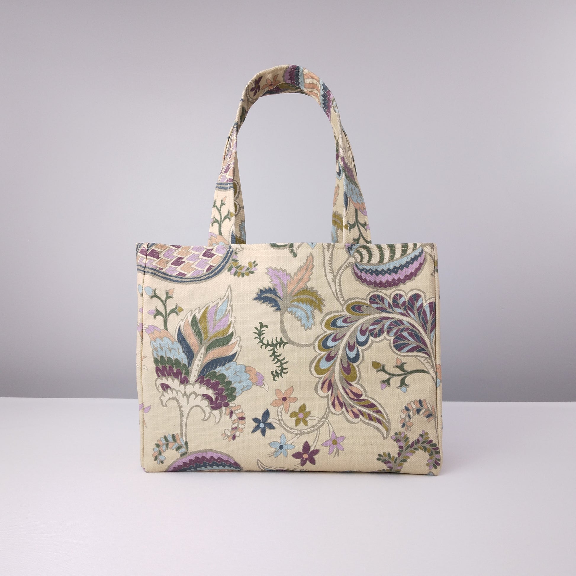 Back view of mini tote bag with multi-colour floral print on beige background