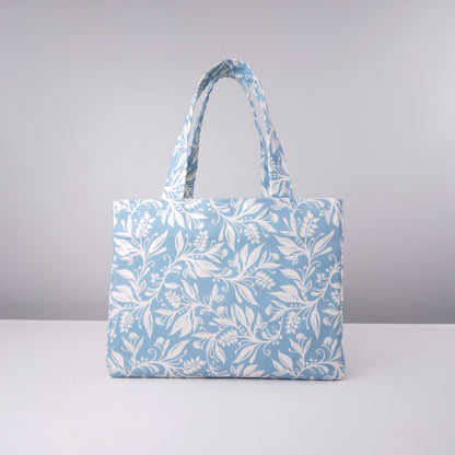 Mini tote bag with white wildflower silhouette design on light blue background