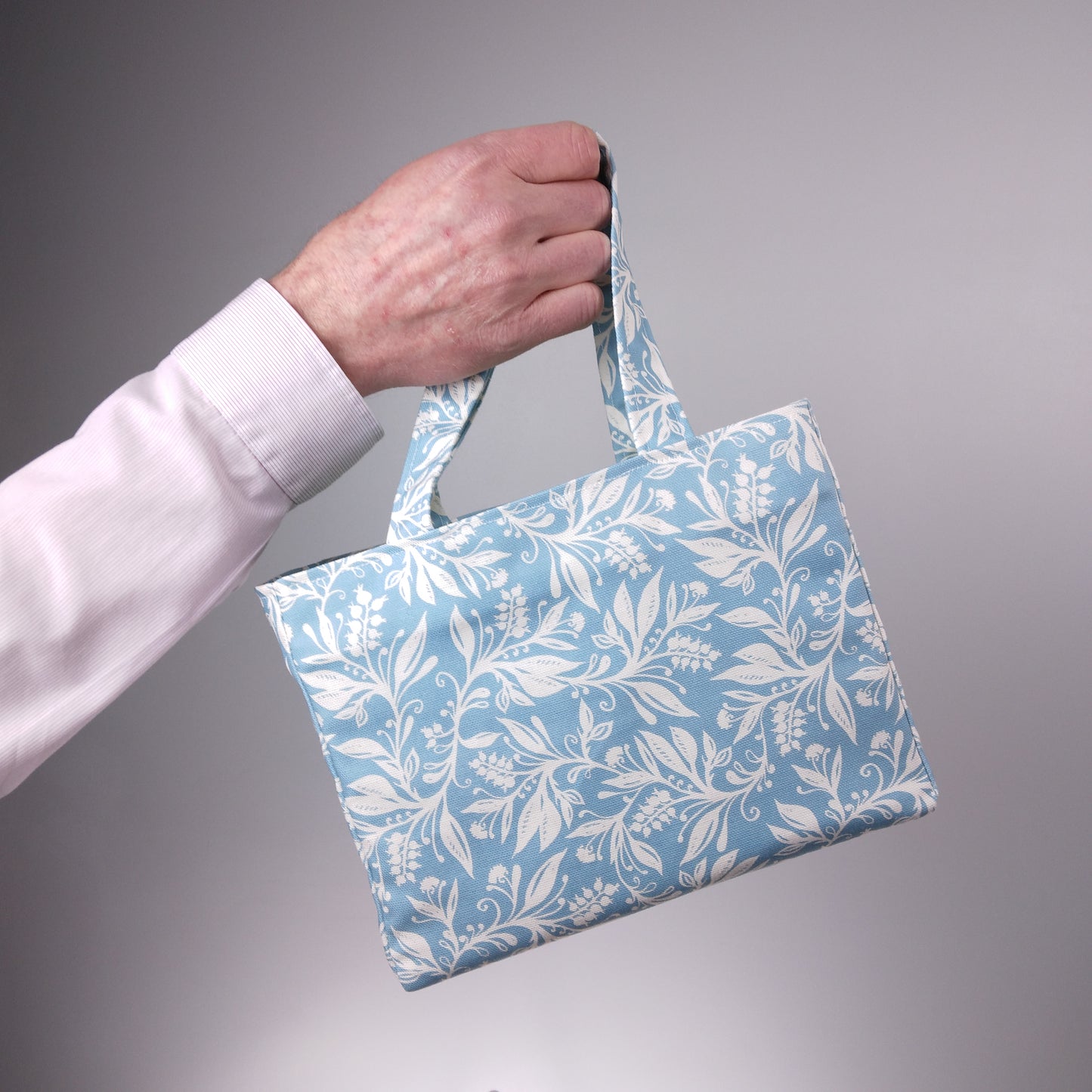 Mini tote bag with white wildflower silhouette design on light blue background