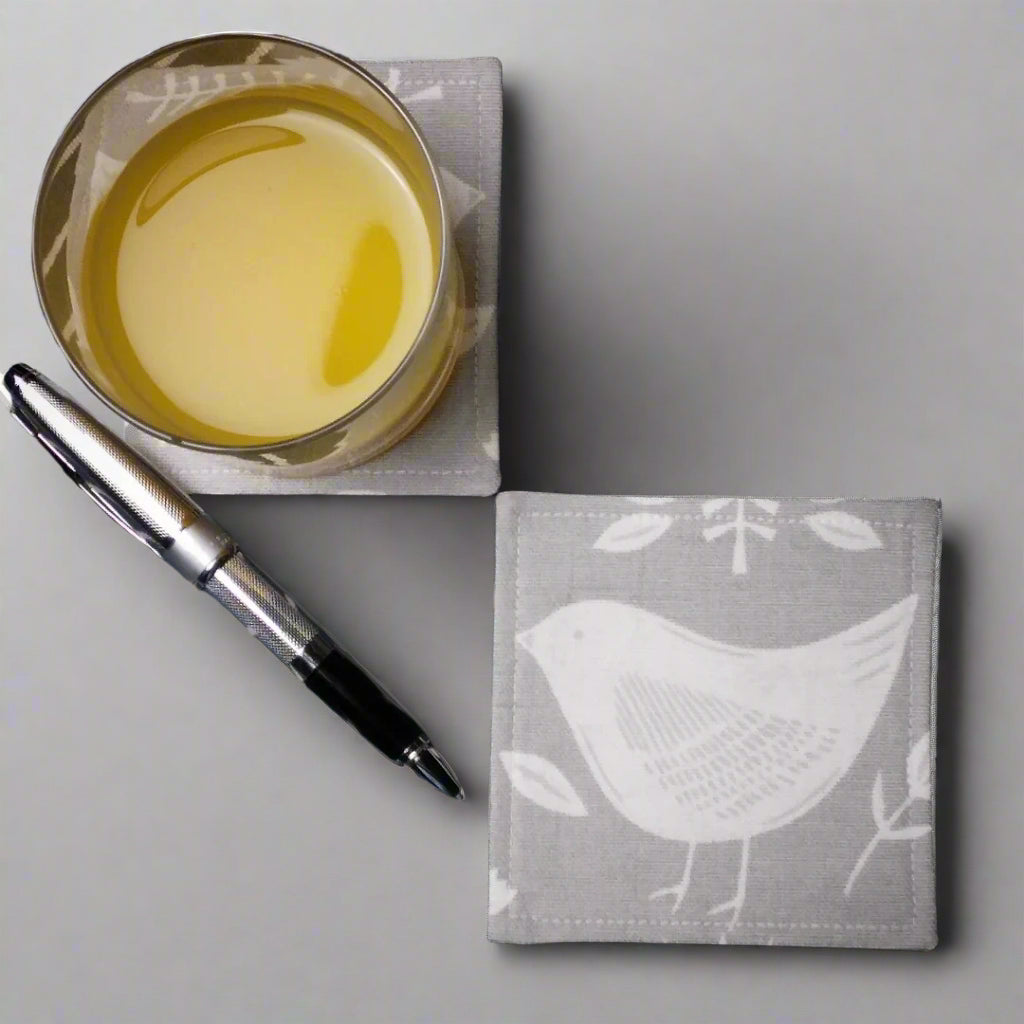 Square coasters with white bird design on grey background