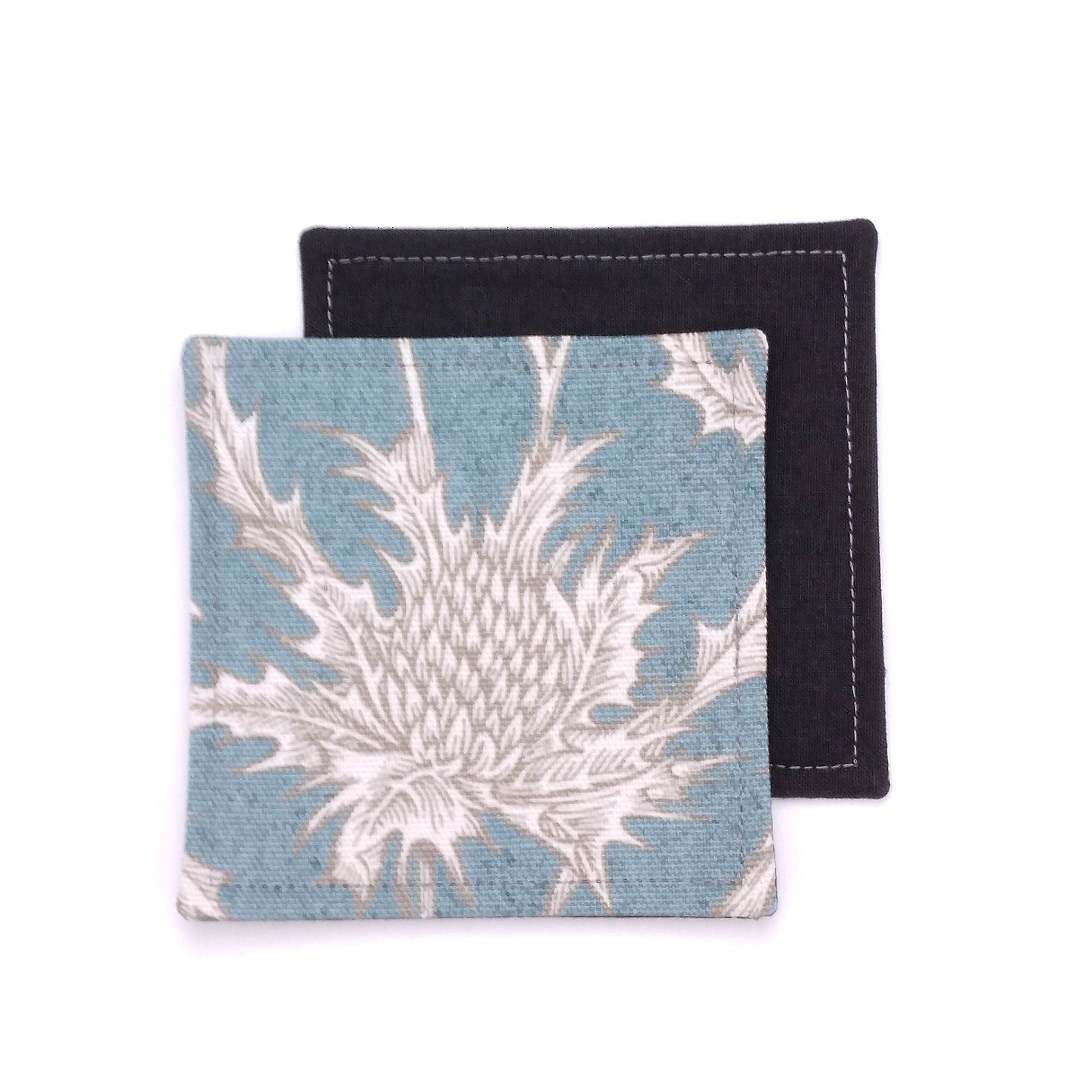 Square coasters with white thistle design on teal blue background