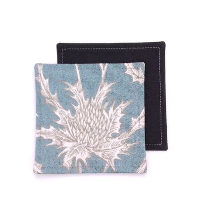 Square coasters with white thistle design on teal blue background