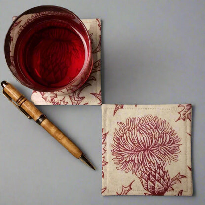 Square coasters with red thistle design on off-white background