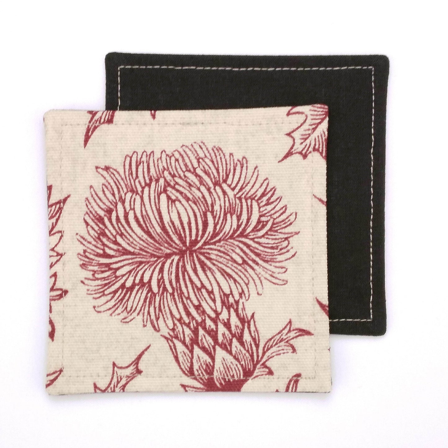 Square coasters with red thistle design on off-white background