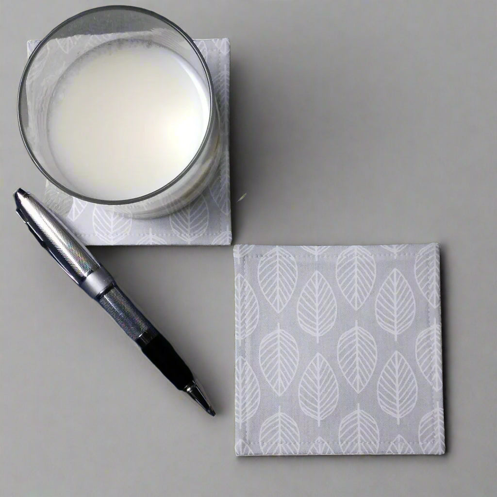 Square coasters with white leaf outline on grey background