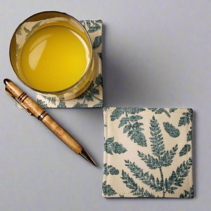 Square coasters with green fern leaves design on beige background