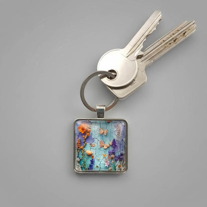 A square glass cabochon keychain with colourful floral collage designs in a metal frame with stainless steel ring