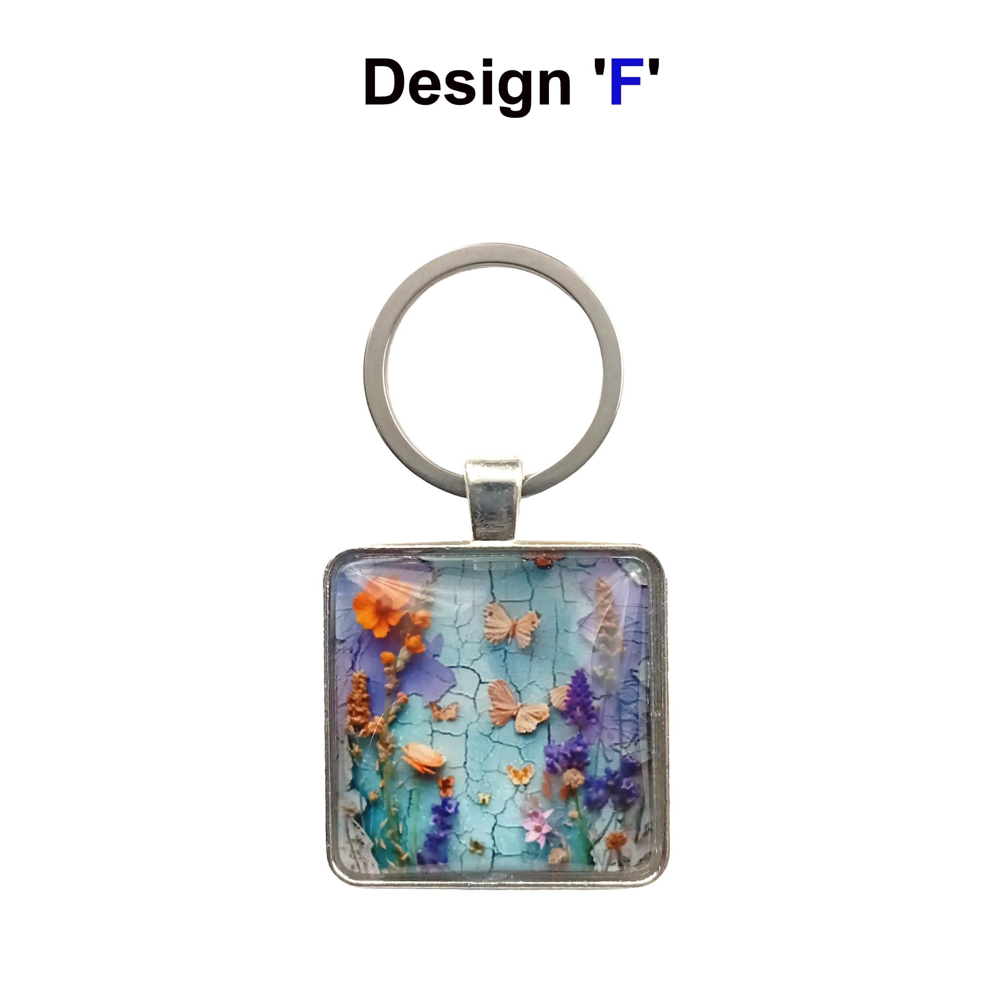 A square glass cabochon keyring with colourful blue and purple floral collage design in a metal frame with steel ring