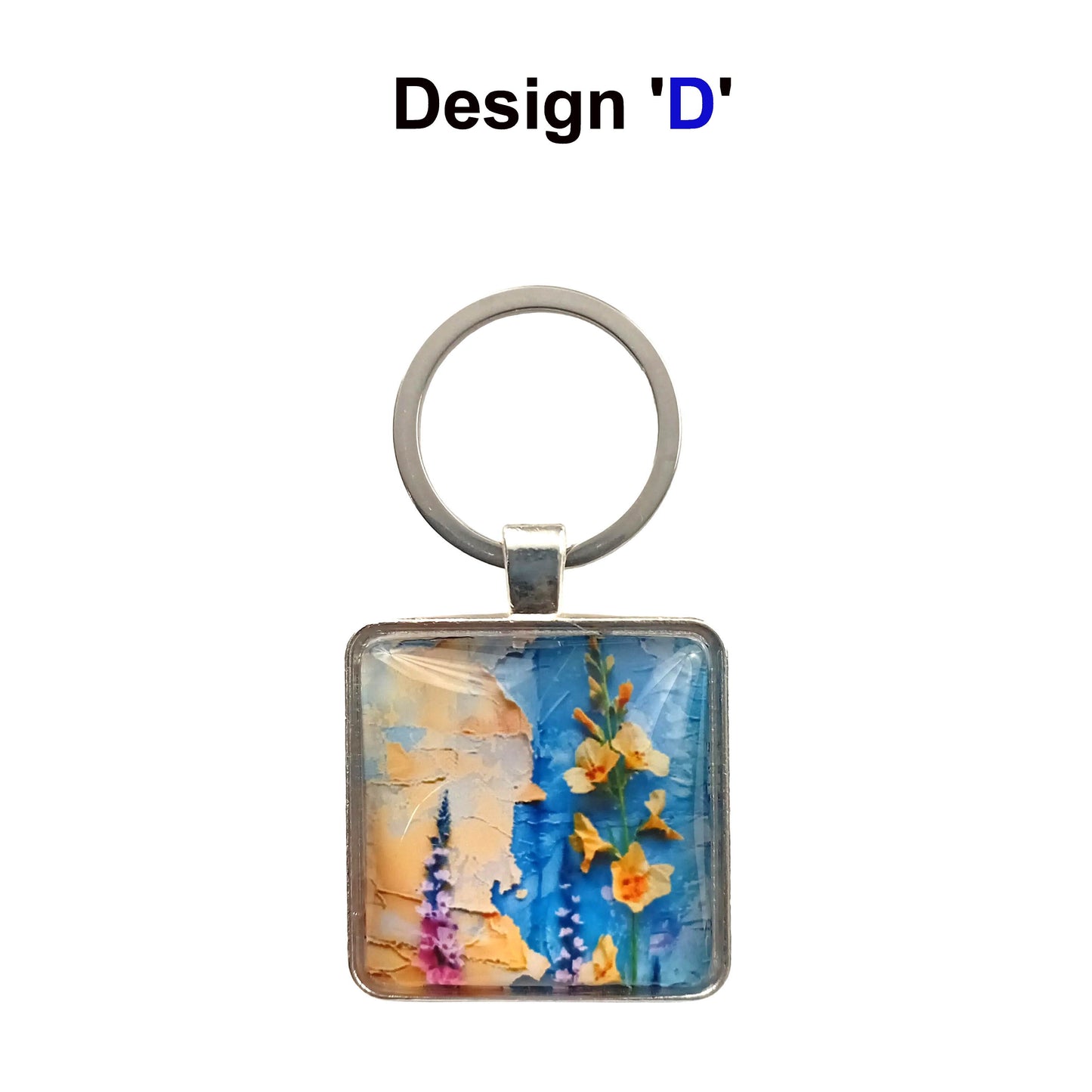 A square glass cabochon keyring with colourful blue and yellow floral collage design in a metal frame with steel ring