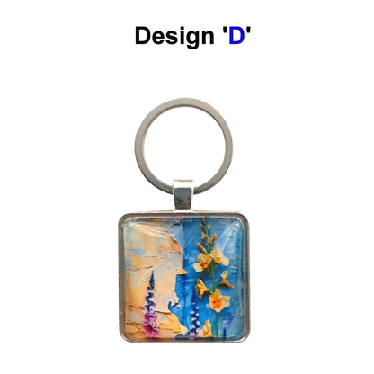 A square glass cabochon keyring with colourful blue and yellow floral collage design in a metal frame with steel ring