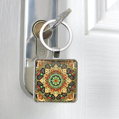 Close up of a square glass cabochon keyring with a colourful mandala pattern