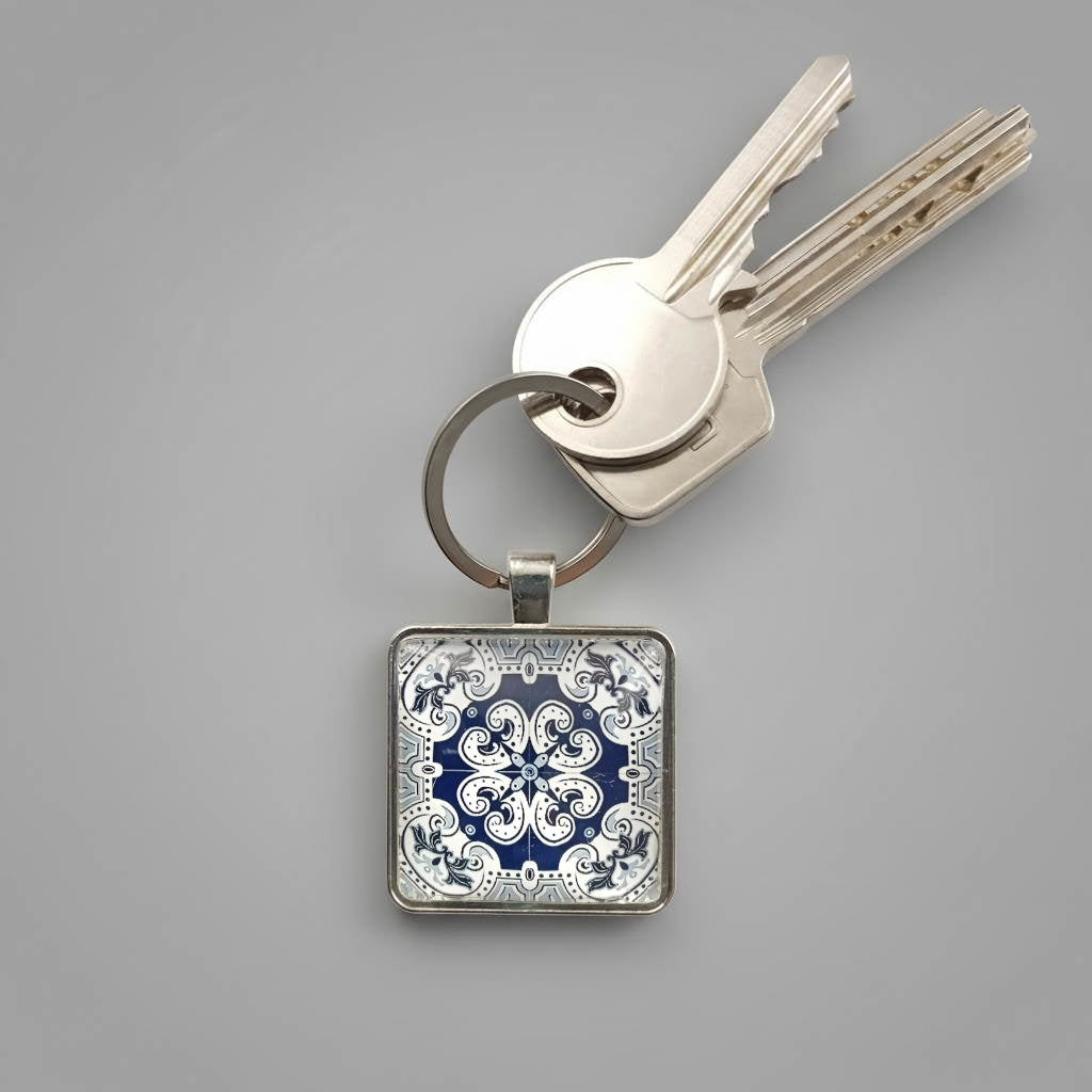 A keyring with colourful tile design beneath a glass cabochon secured in a metal setting with steel split ring