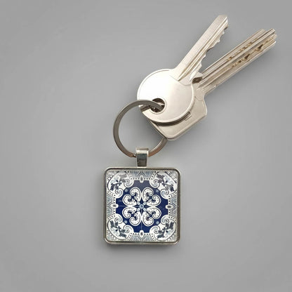A keyring with colourful tile design beneath a glass cabochon secured in a metal setting with steel split ring