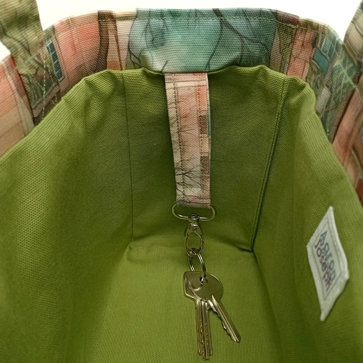 A close up of the metal key clasp with keys inside a handmade mini cotton tote bag with green lining.