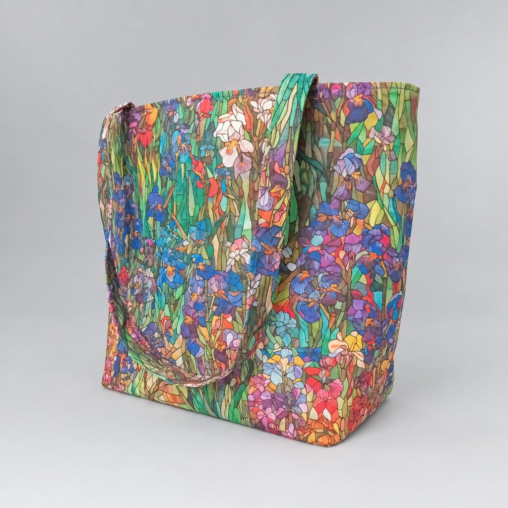 A large handmade cotton tote bag featuring a vibrant, multicoloured floral print with blue and purple irises, and green foliage.