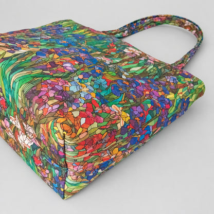 The bottom view of a handmade cotton tote bag with a colourful floral iris pattern, and matching shoulder straps.
