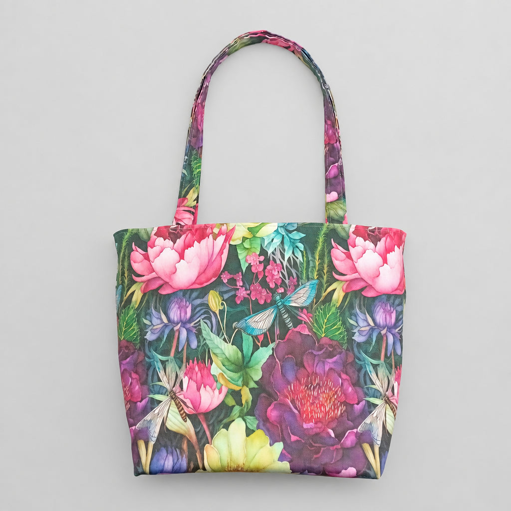 A large handmade cotton tote bag with a vibrant, multicoloured floral print featuring pink, purple, and yellow flowers with green leaves and dragonflies.