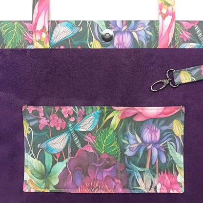 A close-up of a handmade cotton tote bag interior with purple velvet fabric and a colourful floral and butterfly print on the handles, double slip pocket, and attached key clip.