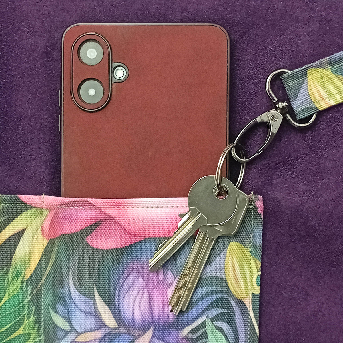 A close-up of a handmade cotton tote bag interior with a colourful botanical slip pocket and mobile phone, and key clip with keys.