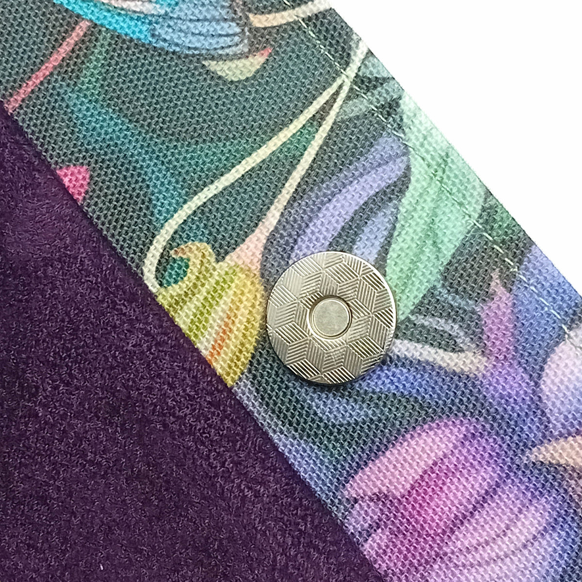 Close-up of a handmade cotton tote bag interior with a dark purple velvet lining and a printed floral trim featuring a multicolour floral design, secured by a magnetic button closure.