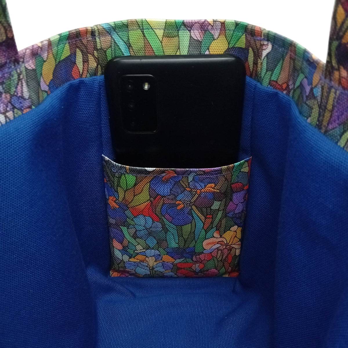 Close-up of a handmade mini cotton tote bag interior with a blue lining and floral patterned interior slip pocket holding a black smartphone.