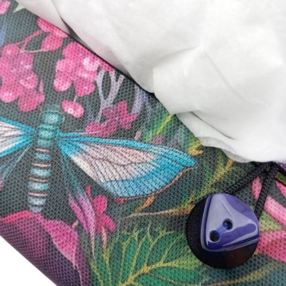 A close up of the button closure on a handmade rectangular cotton tissue box cover with a colourful floral and dragonfly pattern.