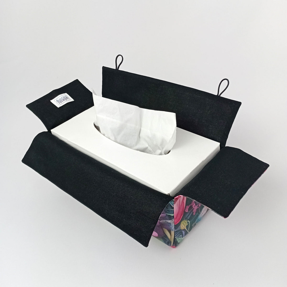 An interior view of a handmade rectangular cotton tissue box cover with a black lining and floral exterior.
