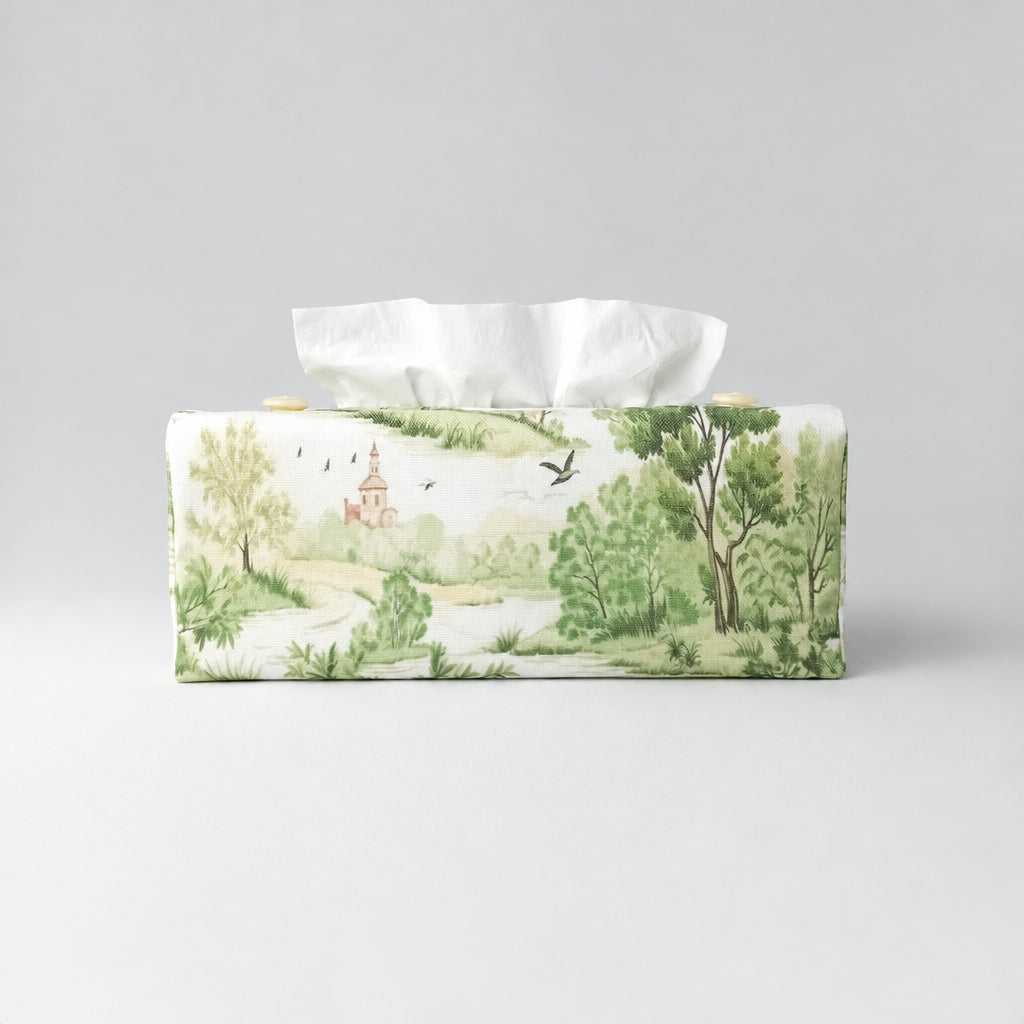 A handmade rectangular cotton tissue box cover with a printed landscape design in soft green, beige, and brown tones on an off-white background.