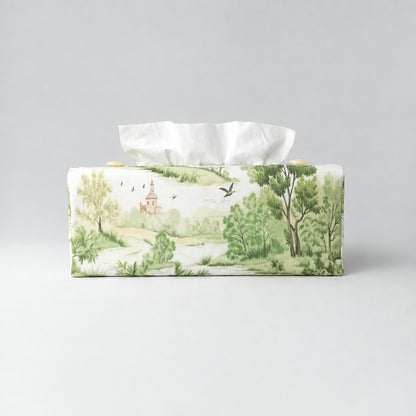 A handmade rectangular cotton tissue box cover with a printed landscape design in soft green, beige, and brown tones on an off-white background.