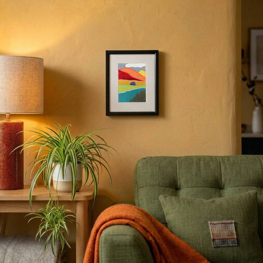 A vertical framed handmade abstract fabric landscape artwork hanging on a living room wall.